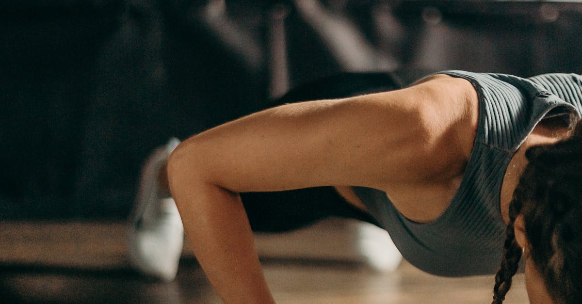 Fit woman doing a dumbbell push-up in a gym, highlighting strength and fitness training.